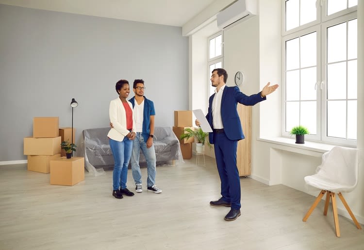 Man in suit holding clipboard showing apartment to interested couple