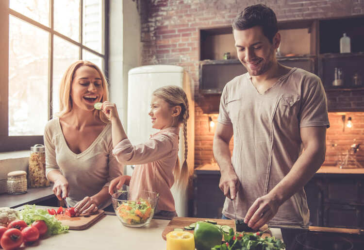 A man and a woman preparing food in a kitchen.