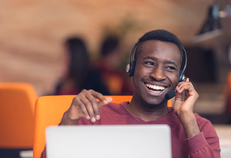 a man sitting in front of a laptop wearing a headset