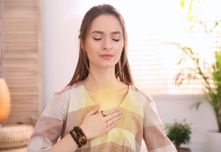 Woman closing her eyes and resting her hand on her chest
