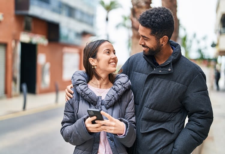 Smiling man standing with arm around smiling woman