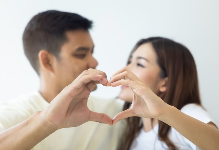 A couple making a heart shape with their hands.