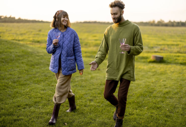 A couple taking a stroll at sunset, enjoying each other's company with a drink in hand.