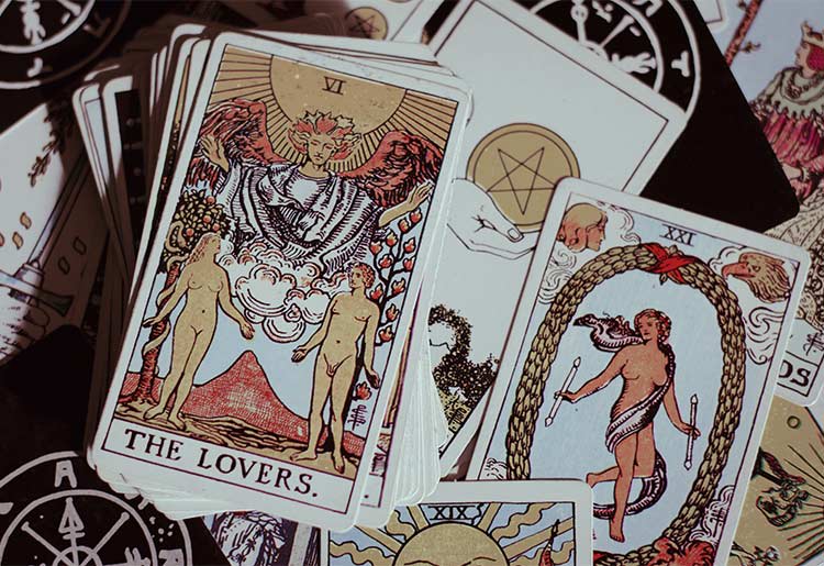 A tarot deck lies on a table showing the "The Lovers" card